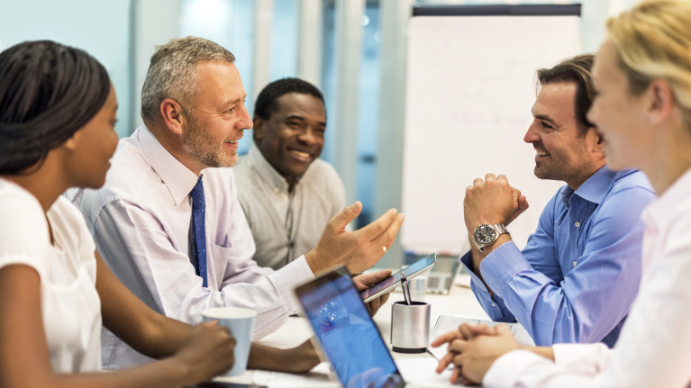 shrm kiosk image of coworkers talking at meeting.