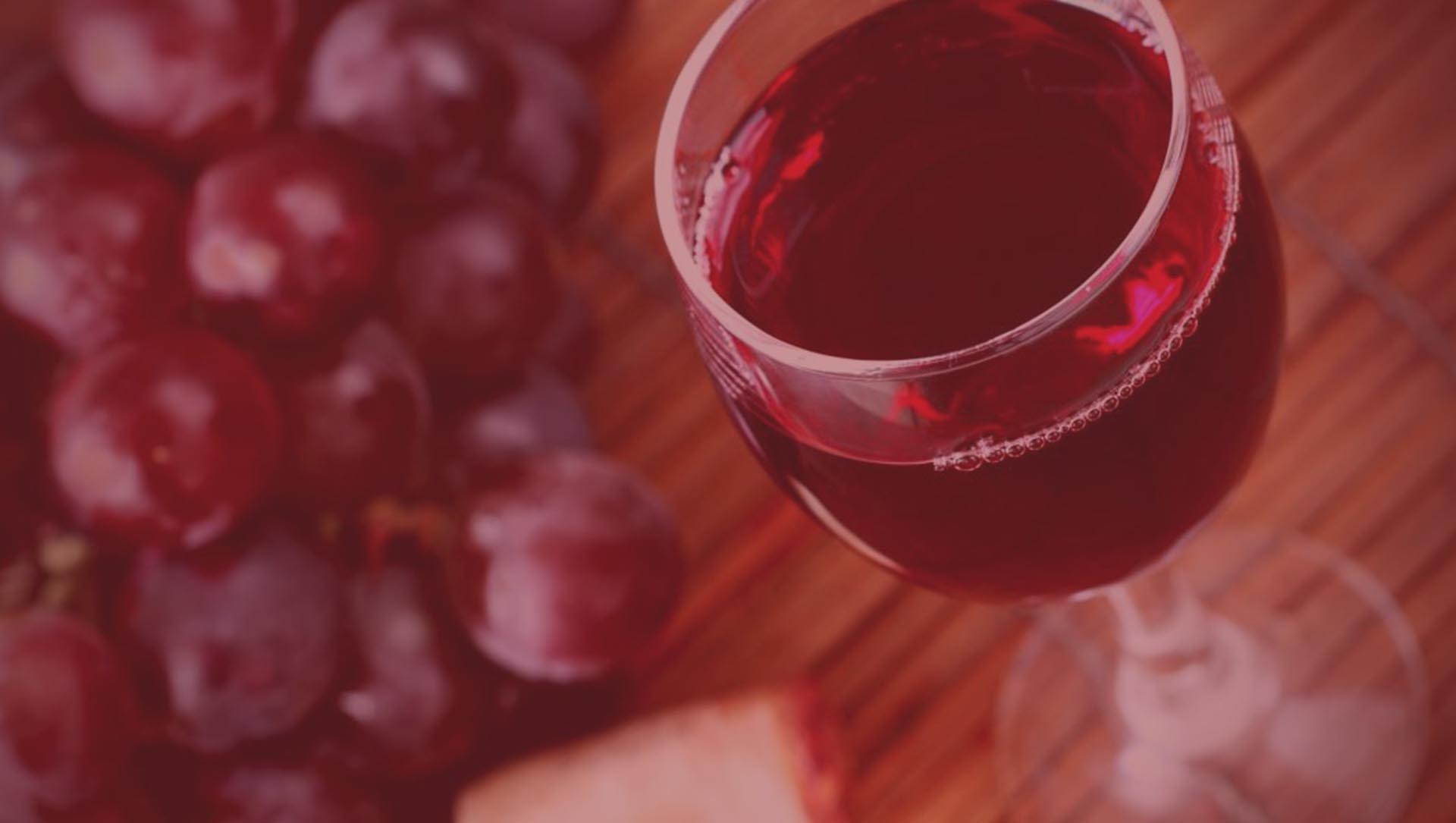 Glass of freshly made wine on display with grapes