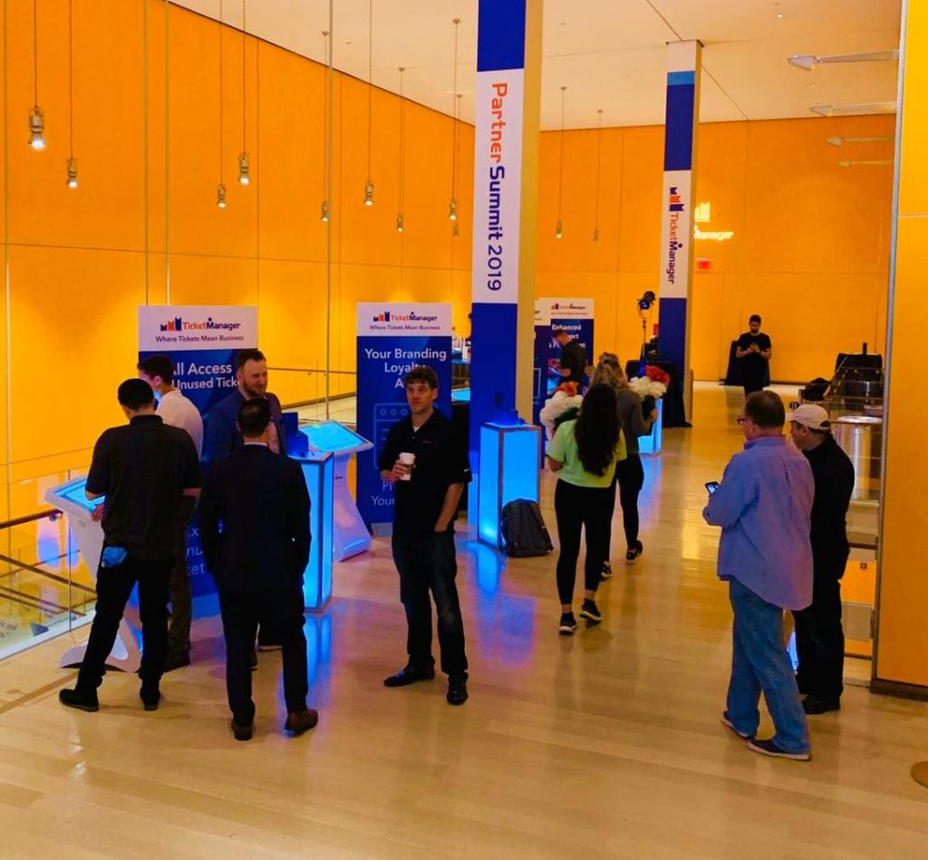 Guests on the trade show floor, learning about Ticket Manager and interacting with our touch tables, customized for Ticket Manager and their guests.